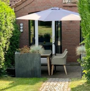 a table and a chair under an umbrella at Boerenhuuske in Margraten