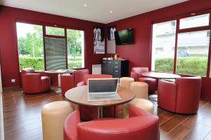 a restaurant with red chairs and a laptop on a table at Campanile Reims Est - Taissy in Reims