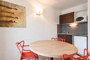 
a kitchen with a table, chairs and a microwave at Residhotel Le Grand Prado in Marseille
