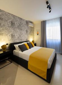 ein Schlafzimmer mit einem großen Bett mit gelben Kissen in der Unterkunft LAUS app. 1 - ART & DESIGN nel cuore di Bari - VIA DANTE ALIGHIERI in Bari