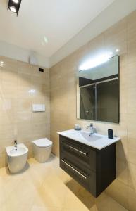 ein Badezimmer mit einem Waschbecken, einem WC und einem Spiegel in der Unterkunft LAUS app. 1 - ART & DESIGN nel cuore di Bari - VIA DANTE ALIGHIERI in Bari