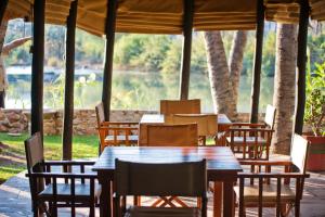 een houten tafel en stoelen met uitzicht op een meer bij Omarunga Epupa-Falls Camp in Opuwo