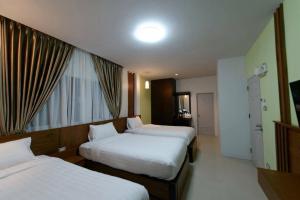 a hotel room with two beds and a window at Kanlaya Place in Chiang Rai