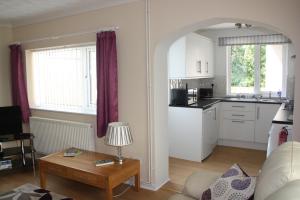 a living room with a table and a kitchen at Ortari@70 in Bishopston
