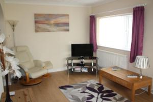 a living room with a tv and a chair and a table at Ortari@70 in Bishopston
