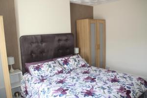 a bedroom with a bed with a floral bedspread at Ortari@70 in Bishopston