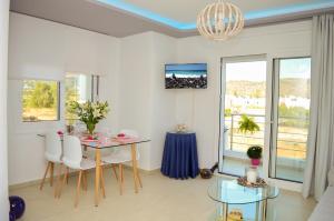 sala de estar con mesa, sillas y lámpara de araña en Meltemi Beach Apartments, en Milatos