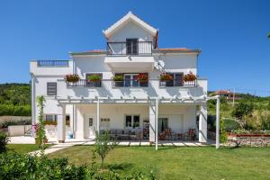 a white house with flowers on the balconies at Apartman Nada in Sinj
