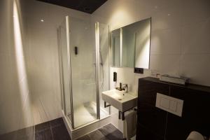 
a bathroom with a shower, sink, and mirror at Design Hotel Glow in Eindhoven

