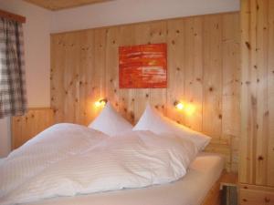 a bedroom with a white bed with wooden walls at Haus Elisabeth Apartments in Obertauern