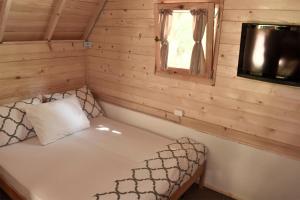 Ce lit se trouve dans une cabane en rondins dotée d'une fenêtre. dans l'établissement TARA INN Resort, à Bastasi
