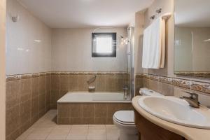 a bathroom with a tub and a toilet and a sink at Macdonald Doña Lola Resort in La Cala de Mijas