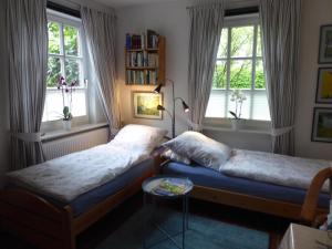 a bedroom with two beds and two windows at Ferienwohnung Landhaus im Grünen in Bad Zwischenahn