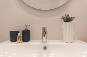 ein Waschbecken mit zwei Flaschen und einer Vase mit Blumen in der Unterkunft Lets Holidays Studio in Tossa in Tossa de Mar + 17 Fotos