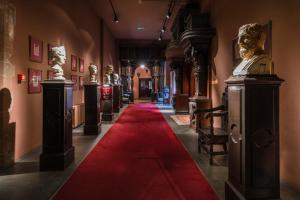 a red carpet in a hallway with statues and art at Coombe Abbey Hotel in Coventry