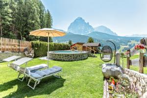a backyard with a pool and chairs and an umbrella at Hotel J&auml;gerheim 3S in Selva di Val Gardena