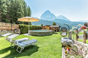 un patio trasero con piscina, sillas y sombrilla en Hotel Jägerheim 3S en Selva di Val Gardena