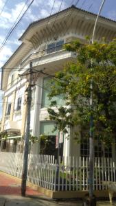 a white house with a white fence and a tree at Daffodils Spice Court in Cochin