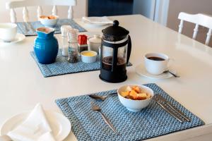 a table with cups of coffee and a bowl of fruit at i-LOLLO Bed & Breakfast at the River Mouth in St Francis Bay