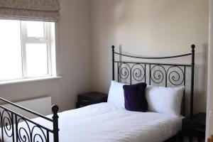 um quarto com uma cama preta com lençóis brancos e uma janela em Atlantic Rose Cottage em Doolin