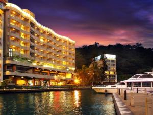 a hotel and a boat in a river at night at Hotel Del Lago in Yuchi