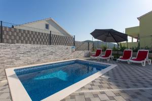 a swimming pool with two chairs and an umbrella at Villa Supuk in Vinišće