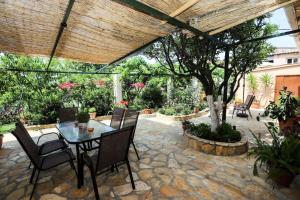 eine Terrasse mit einem Tisch, Stühlen und einem Baum in der Unterkunft Garden House Kastellani in Kastellánoi
