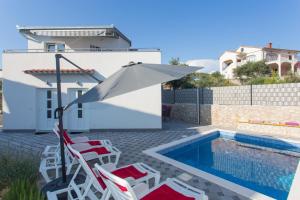 a group of chairs and an umbrella next to a swimming pool at Villa Supuk in Vinišće