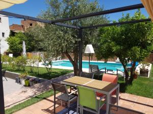 un patio con tavolo, sedie e piscina di Casa los tejones a Pinos del Valle