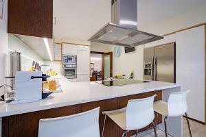 a kitchen with white counters and white chairs at BestVillas Apúlia Relax in Esposende