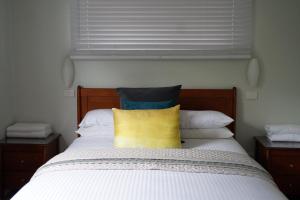 a bed with a white comforter and pillows at Beltana Villas in Pokolbin