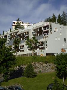 un gran edificio blanco con árboles delante de él en Résidences du Chamossaire, en Leysin