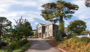 a house with a tree in the driveway at FSC Slapton Ley Hostel in Kingsbridge
