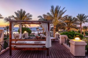 a bed on a deck with palm trees and the ocean at Cleopatra Luxury Resort Sharm El Sheikh in Sharm El Sheikh