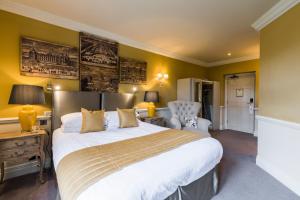 a bedroom with a large bed and a chair at Coombe Abbey Hotel in Coventry