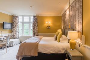 a bedroom with a large bed and a desk at Coombe Abbey Hotel in Coventry