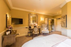 a bedroom with a bed and a desk and a mirror at Coombe Abbey Hotel in Coventry