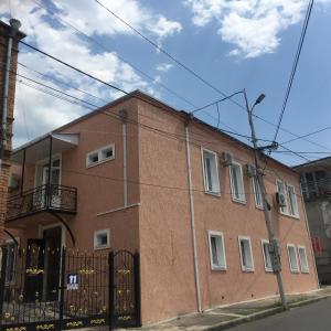 un bâtiment en briques rouges avec une clôture noire devant lui dans l'établissement HOTEL COMFORT, à Koutaïssi