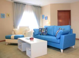 ein Wohnzimmer mit einem blauen Sofa und einem Couchtisch in der Unterkunft Alocassia Serviced Apartments in Singapur