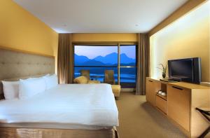 una camera d'albergo con un grande letto e una TV di Hotel Del Lago a Yuchi