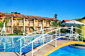 un complexe avec une piscine entourée d'un parasol dans l'établissement Resid. Moradas de Israel - Tonziro, à Porto Seguro