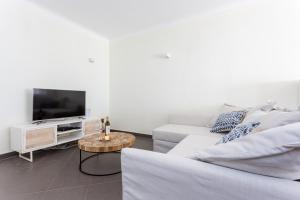 ein weißes Wohnzimmer mit einem weißen Sofa und einem TV in der Unterkunft Sitio da Ponte Family Apartment in Lagos