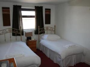 a room with two beds and a window with a window at Beverley Inn & Hotel in Edenthorpe