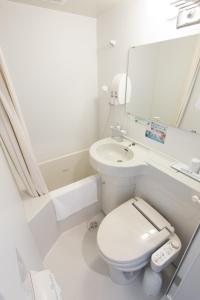 a white bathroom with a toilet and a sink at Super Hotel Tokyo JR Shinkoiwa in Tokyo