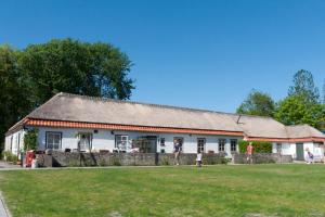 a large white house with a grass field in front of it at Hof Aan Zee in Dishoek