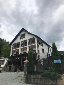 a large white building with a fence in front of it at Vila Confort in Borşa
