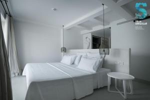 a white bedroom with a white bed and a table at Villa Singular in San José