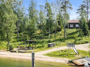 a playground next to the water with a house at Holiday Home Kalatiira 3 by Interhome in Strandby