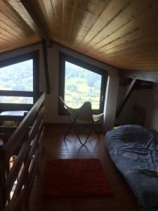 a bed and a chair in a room with two windows at Charmant T3 Bussang, Vosges, vue imprenable in Bussang