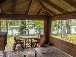 un patio con mesas y bancos en una cabaña en Holiday Home Jukola by Interhome, en Ruottila
